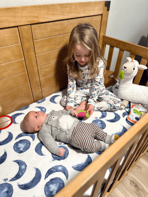 Brother and sister sitting in crib together