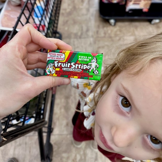Fruit Stripe gum with girl standing by it