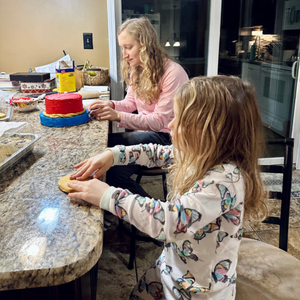 Girl and daughter cake decorating together at kitchen counter