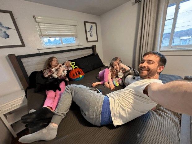 Family of four with pets laying on bed