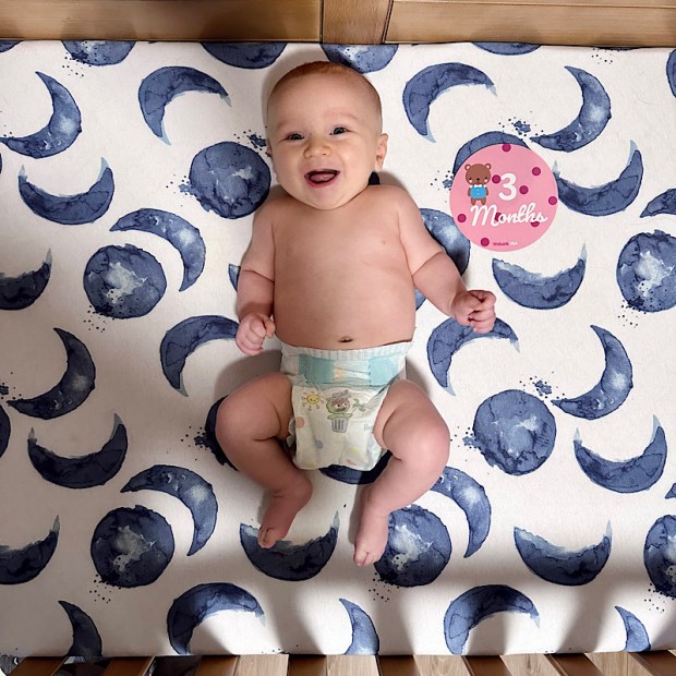 Three month old baby boy smiling in crib
