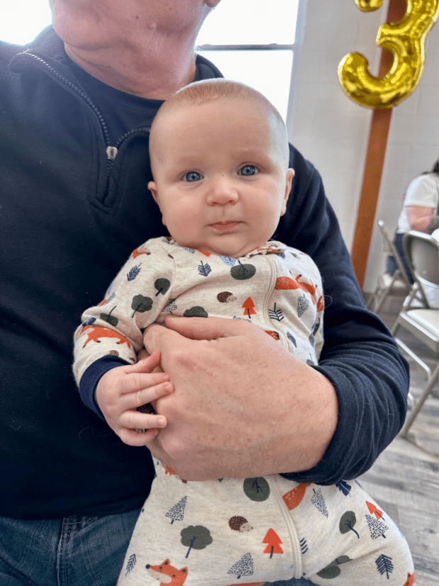 Three month old baby boy sitting on grandpa's lap