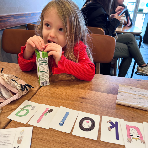 Girl drinking apple juice at Starbucks with letter flash cards