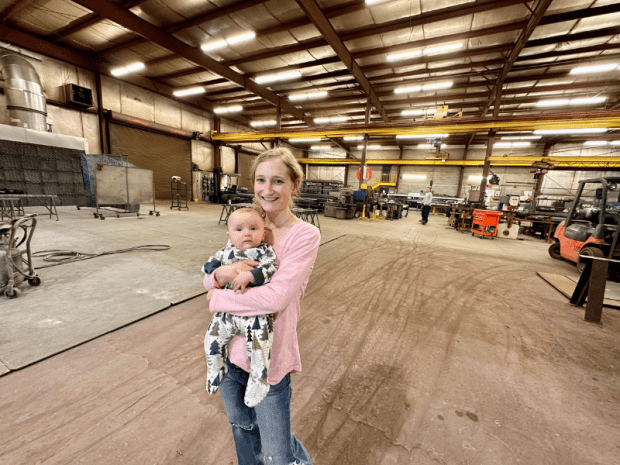 Mom holding baby boy in steel fabrication shop