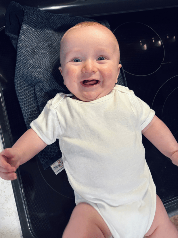 Baby boy wearing white onesie and smiling