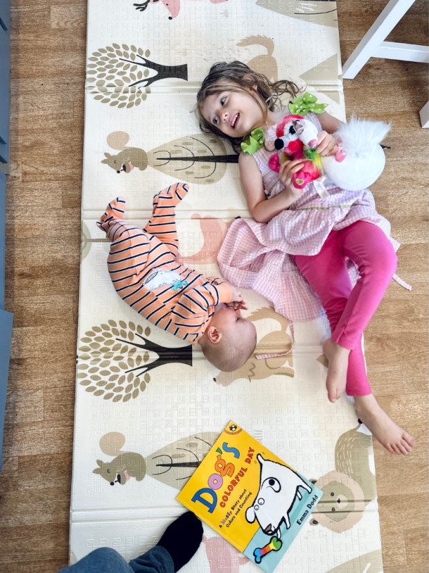 Girl and baby brother laying on play mat