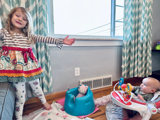 Girl and baby brother playing on floor with blankets