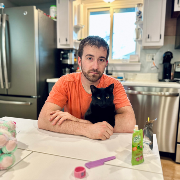 Black cat sitting in guy's arms