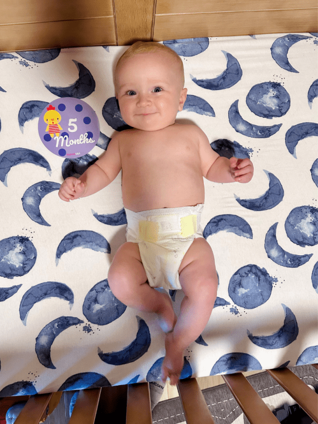Five month old baby boy laying in crib