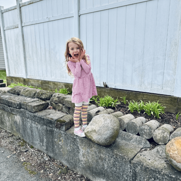 Young girl standing on retaining wall