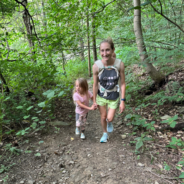 Mom hiking with young girl and baby on her back in carrier