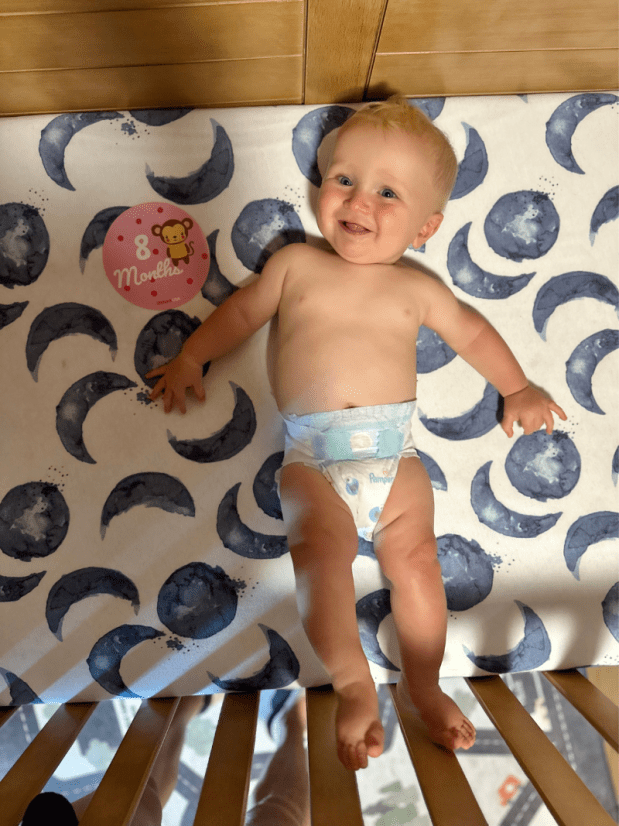 Eight month old baby boy laying in crib