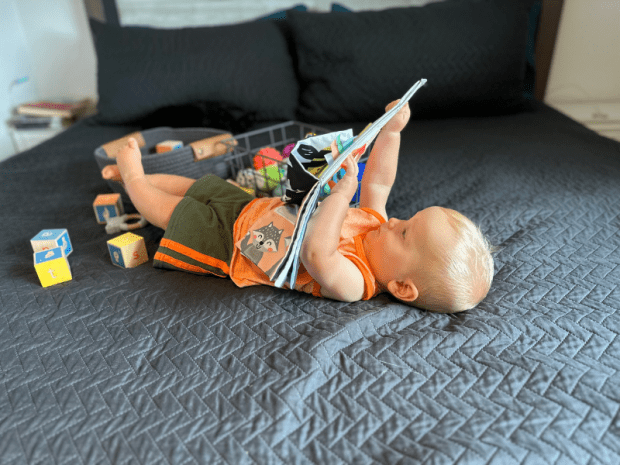 Baby boy laying on bed and playing with toys