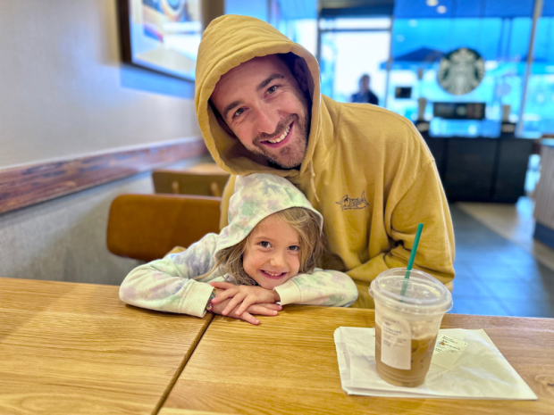 Dad and young daughter wearing hoodies in Starbucks