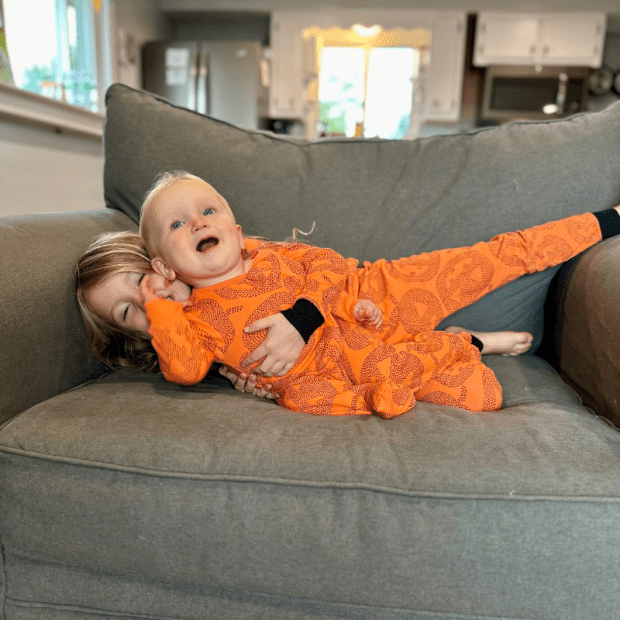 Sister hugging baby brother on couch