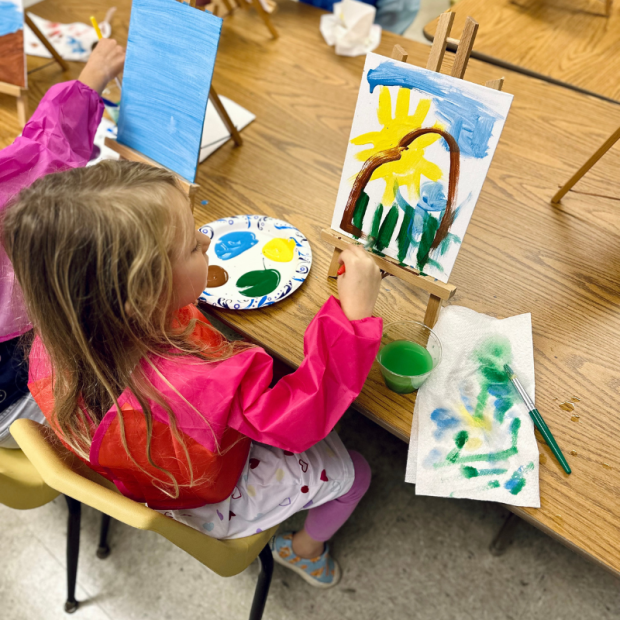 Kindergartener painting a canvas