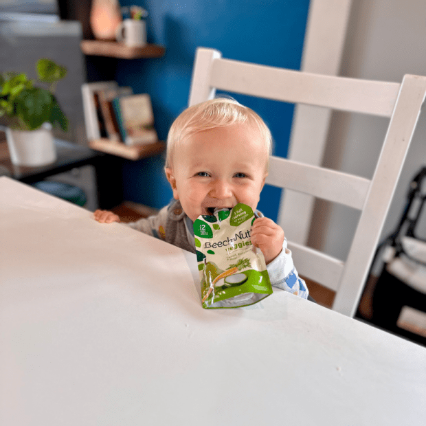 Baby boy eating Beechnut baby food pouch at table