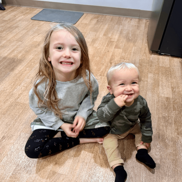 Girl sitting on kitchen floor with baby brother