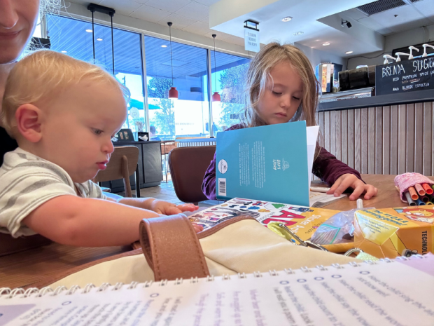 Young girl and baby doing school at Starbucks