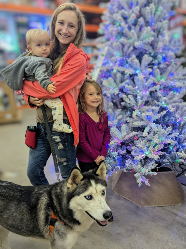 Mom with baby boy, daughter, and husky in Home Depot by Christmas trees