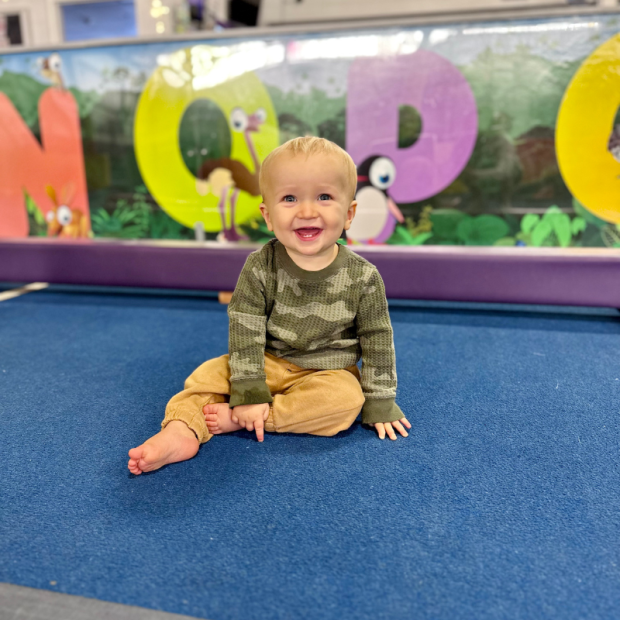 Baby boy sitting on floor at gymnastics gym