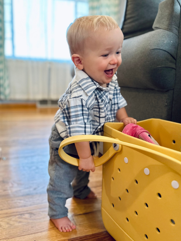 Baby boy standing with yellow bogg bag