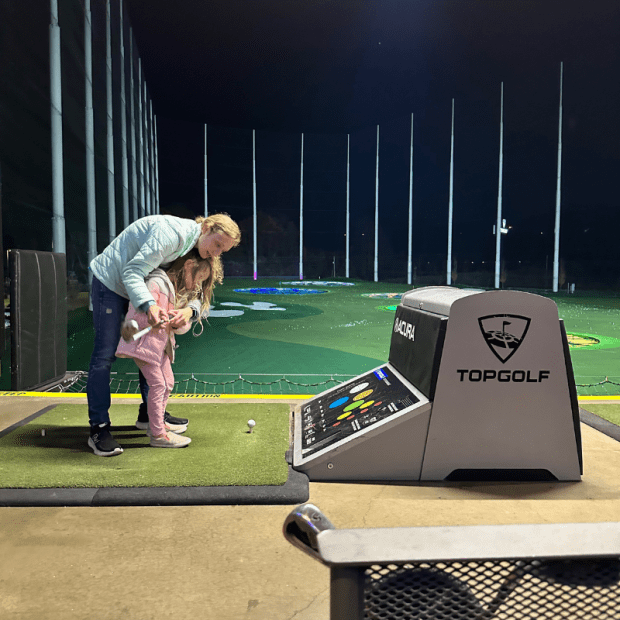Mom at Top Golf with young daughter