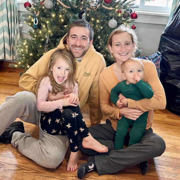 Family photo in front of Christmas tree with mom, dad, girl, and baby