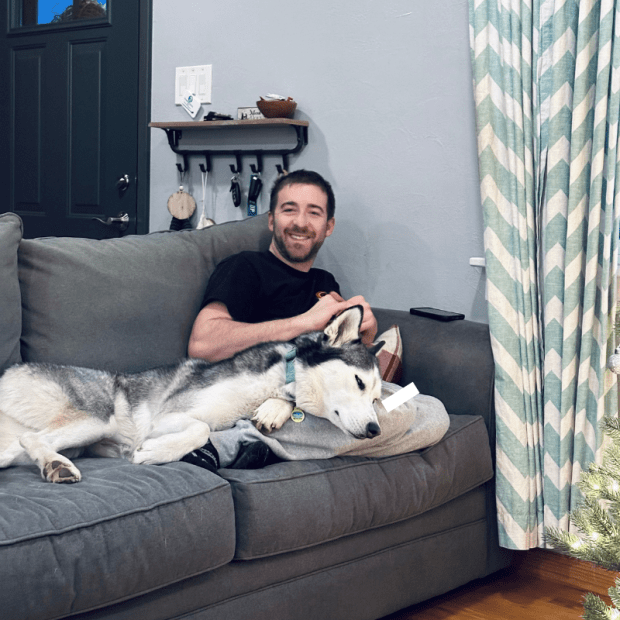 Guy sitting on couch with Siberian husky