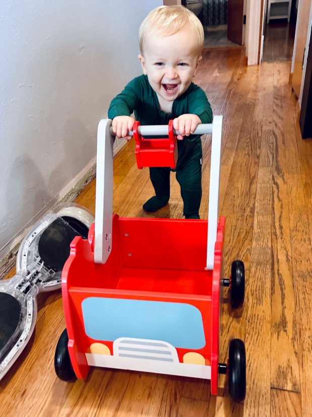Baby boy pushing fire truck walker