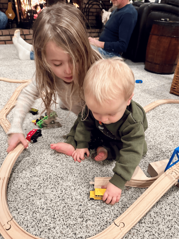 Big sister and baby brother playing with train set