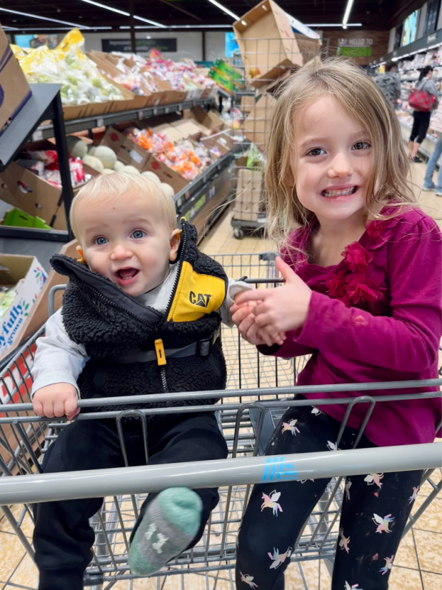 Baby boy and big sister in Aldi shopping cart together