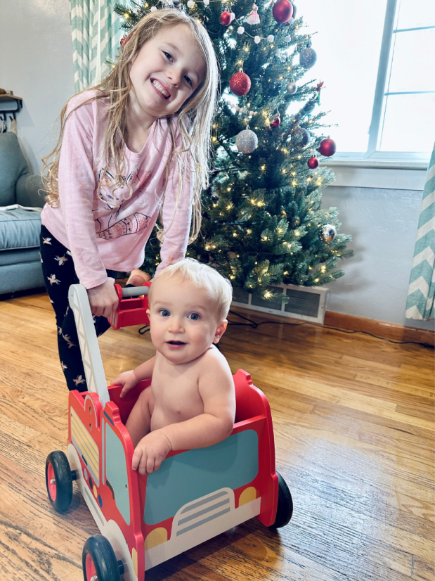 Big sister pushing baby brother in firetruck baby walker toy