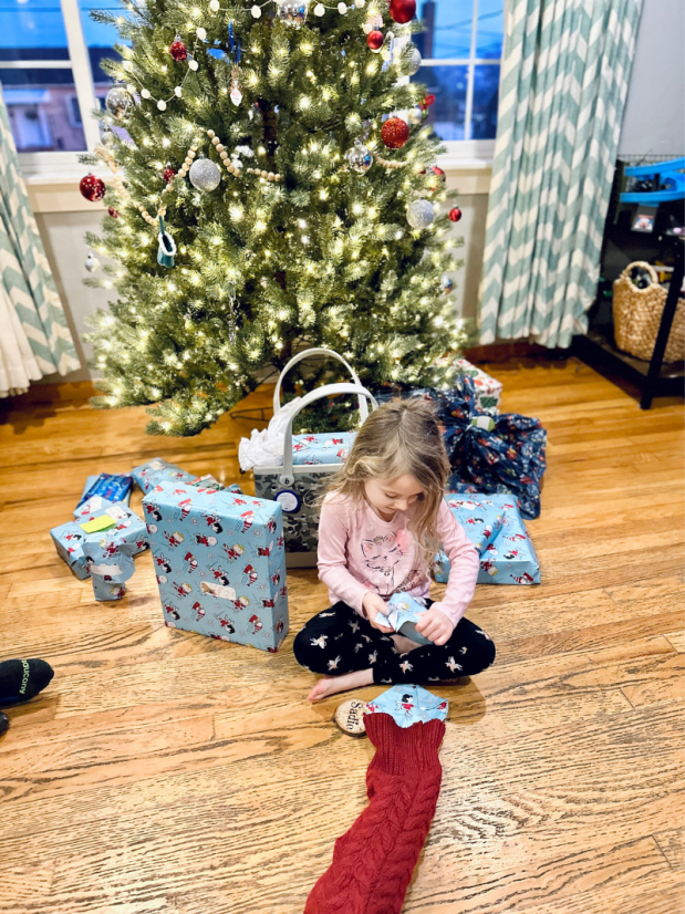 Girl sitting on floor opening Christmas gifts