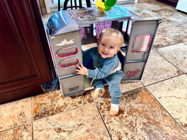 Baby boy sitting in doll camper