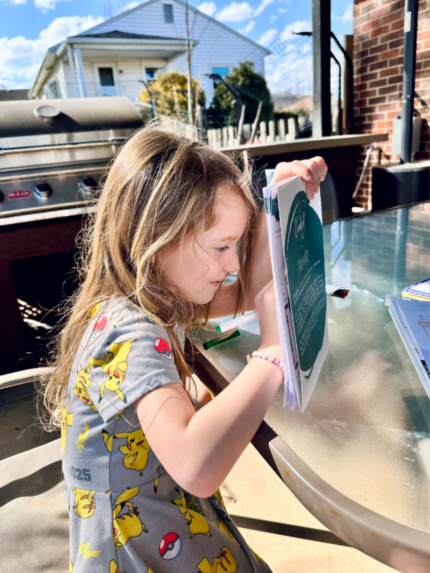 Girl wearing Pikachu dress doing schoolwork outside