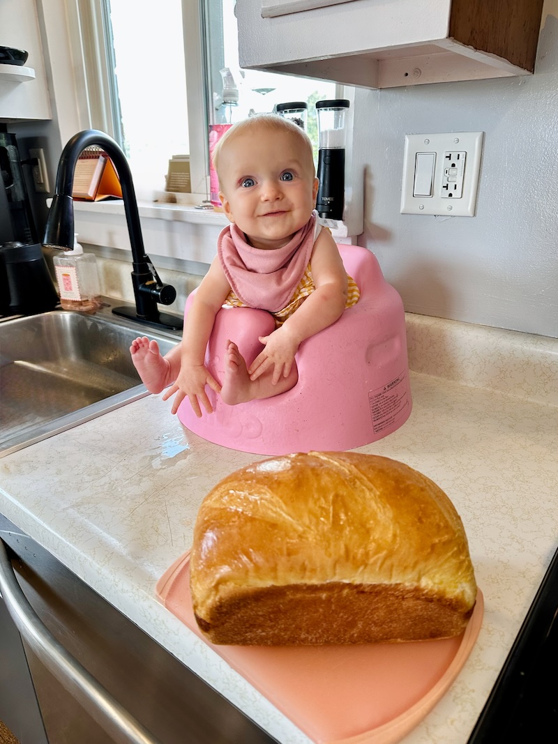 Baby in bumbo in front of loaf of bread