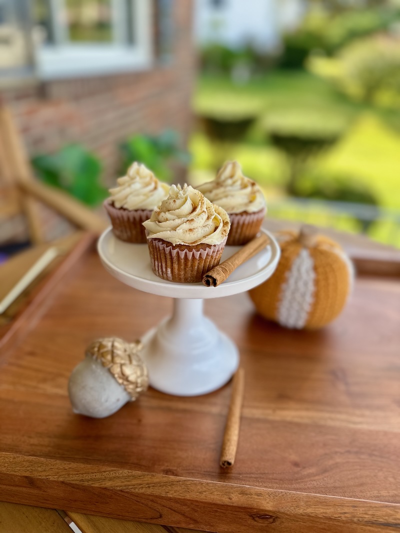 Pumpkin spice cupcakes with cinnamon maple buttercream sitting on cake stand