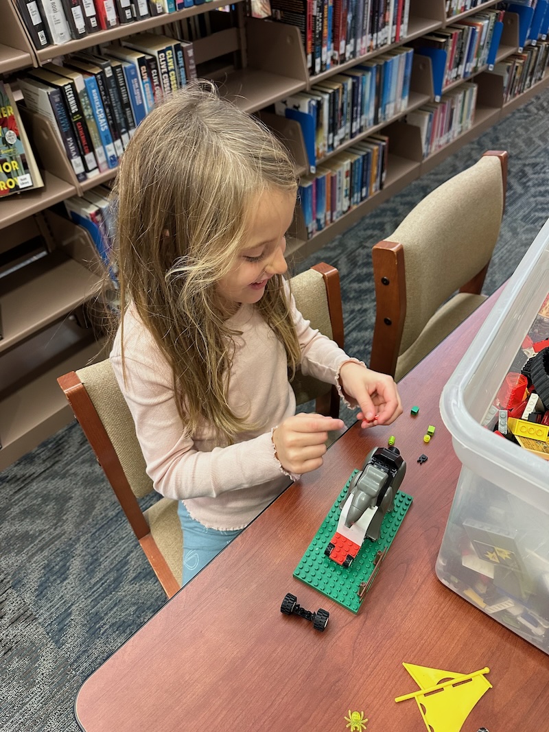 Girl building with Legos in library