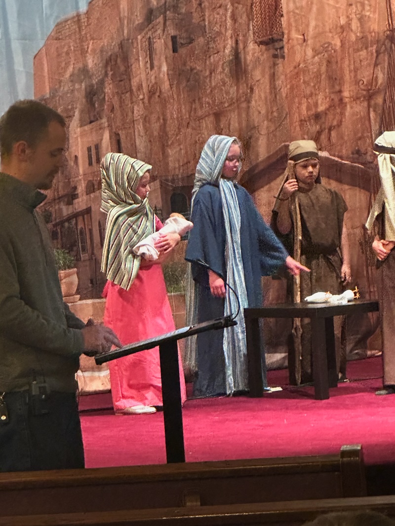 Girl in nativity play holding baby Jesus