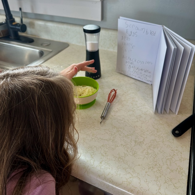 Girl cooking from cookbook