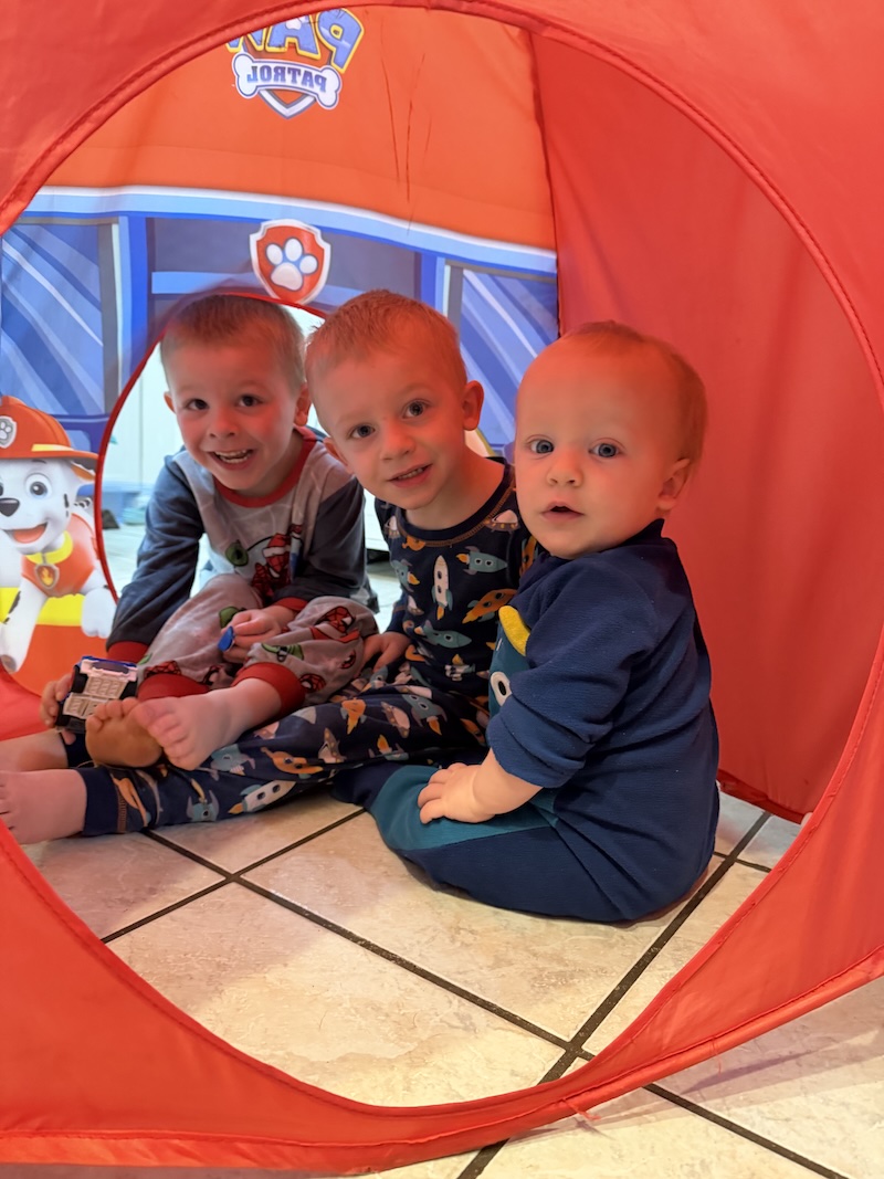 Three boys sitting in play tent
