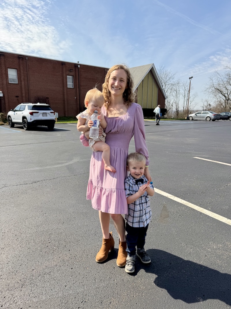 Mom holding baby standing by toddler at church