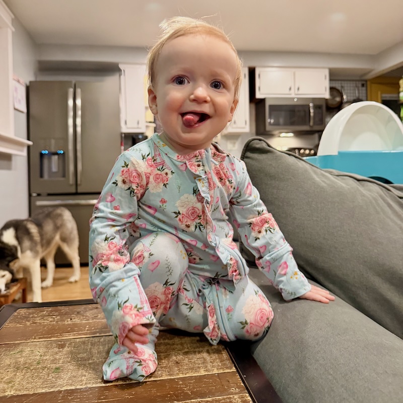 Baby girl sitting on coffee table with tongue out