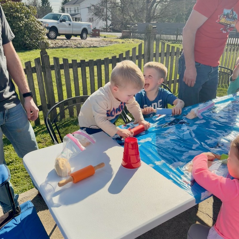 Boys making homemade pizza outside