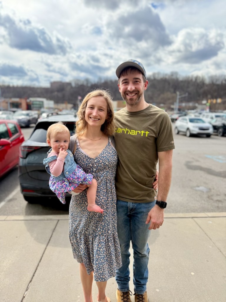 Mom and dad with one year old baby girl in parking lot