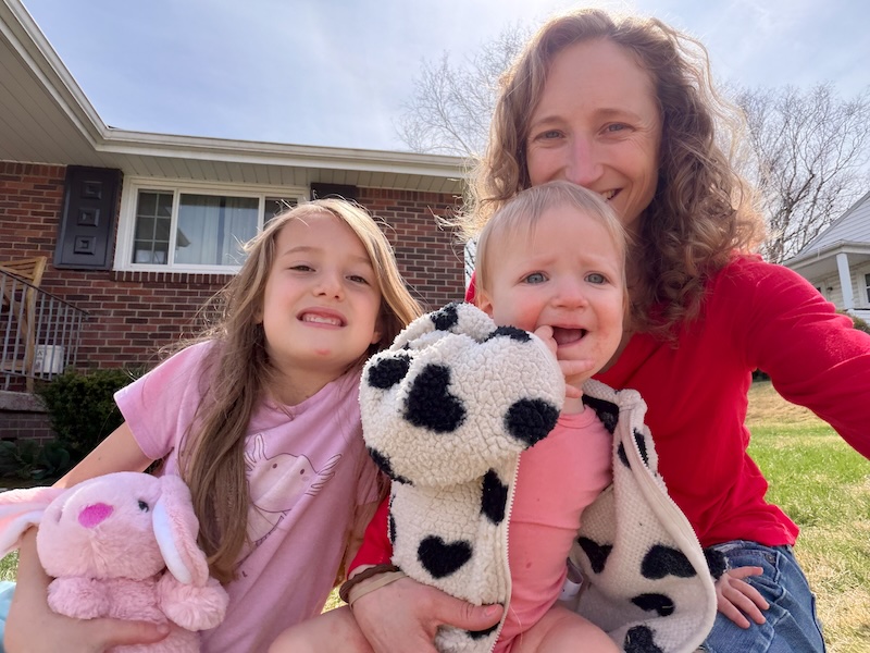 Mom and daughters sitting outside in grass