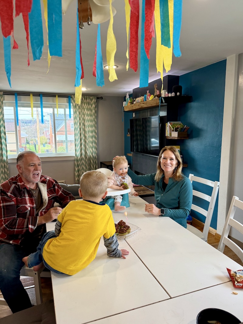 Family sitting at kitchen table with cupcakes and streamers