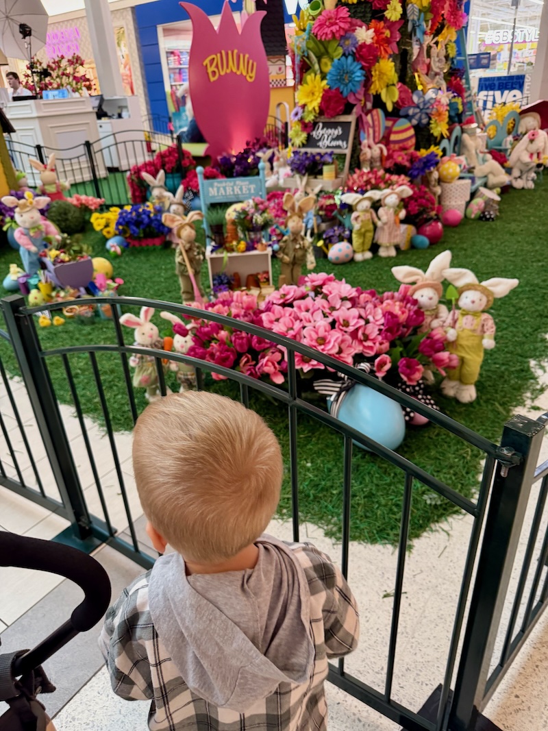 Toddler boy looking at Easter display at mall