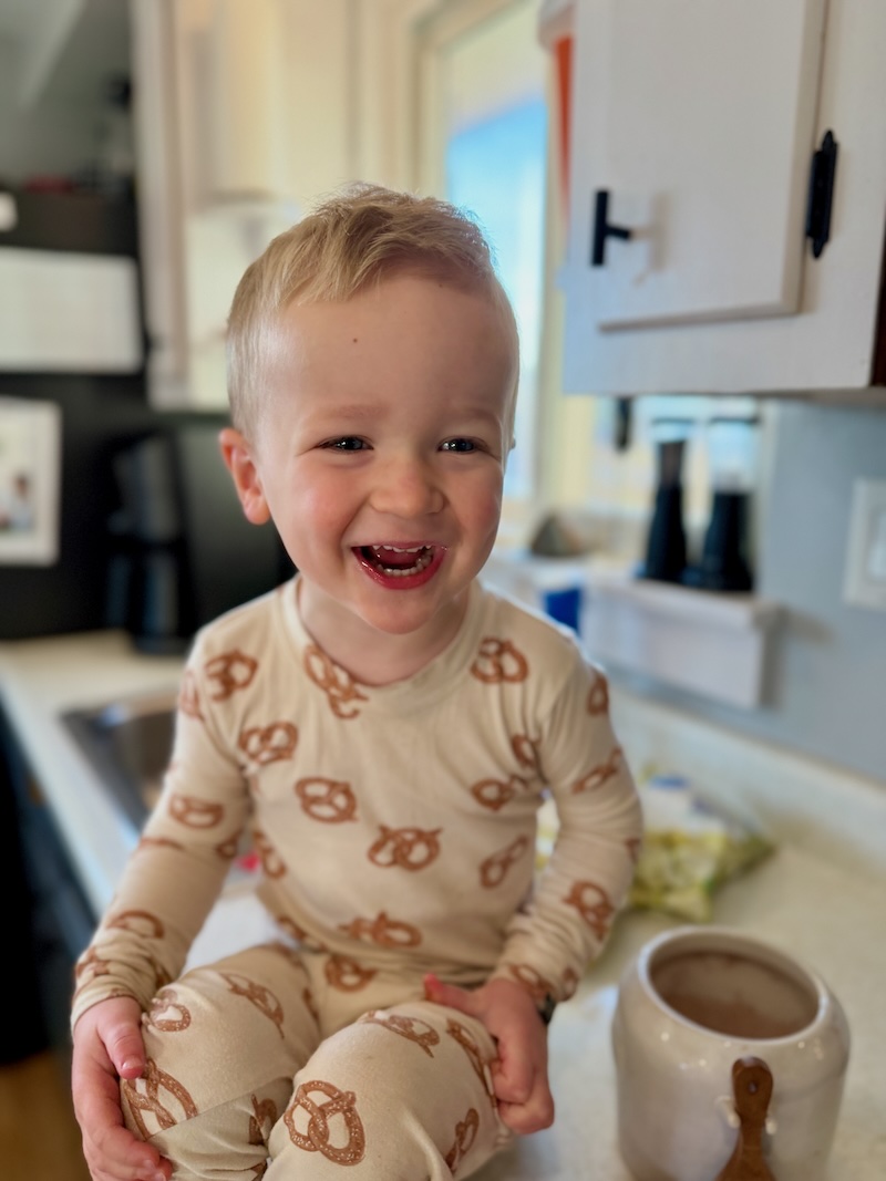 Toddler boy sitting on kitchen counter with hot cocoa mix